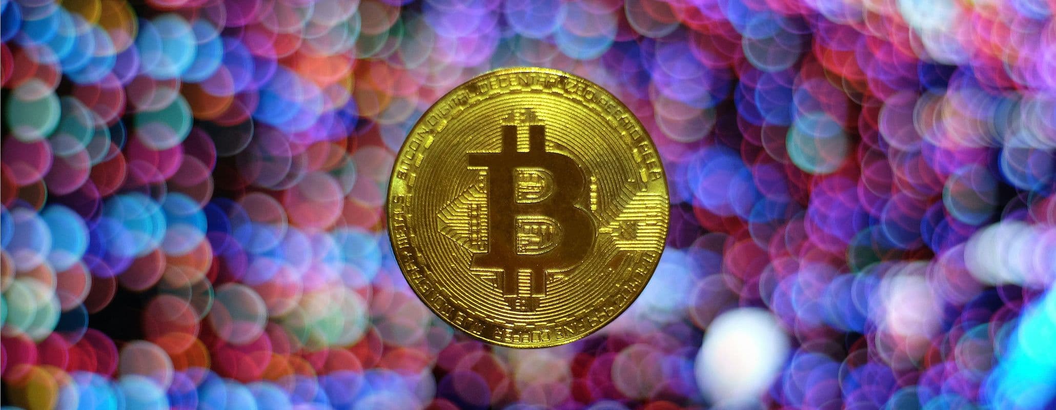 Image of a bitcoin against a multicoloured and blurred background